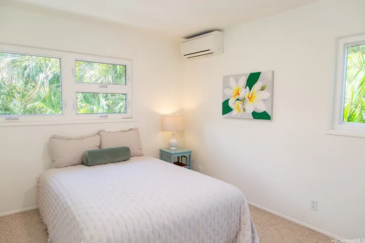 A bright secondary bedroom with a split AC and windows along the end-unit side bringing in plenty of natural light. | Enhanced