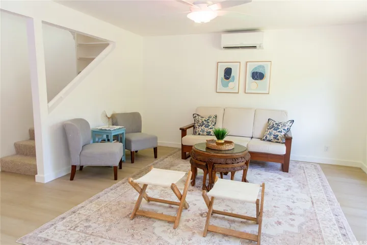 Comfortable and inviting living room with split AC, updated flooring and a bright, airy feel, plus convenient access to the upper level just off the main living space.