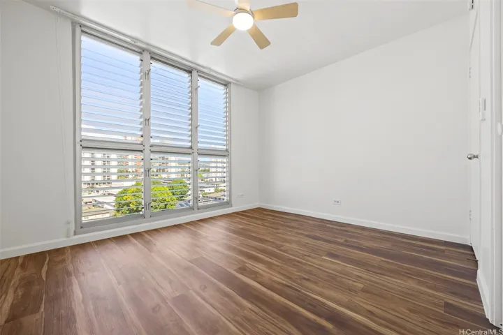 A primary bedroom with views of Manoa Valley and Honolulu city lights.  Luxury vinyl flooring runs through out.