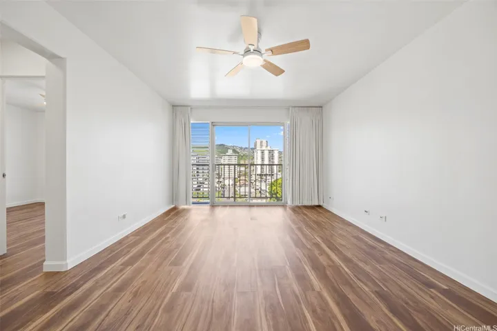 An open living room with views of Manoa Valley and Honolulu city lights.  Luxury vinyl flooring runs through out.