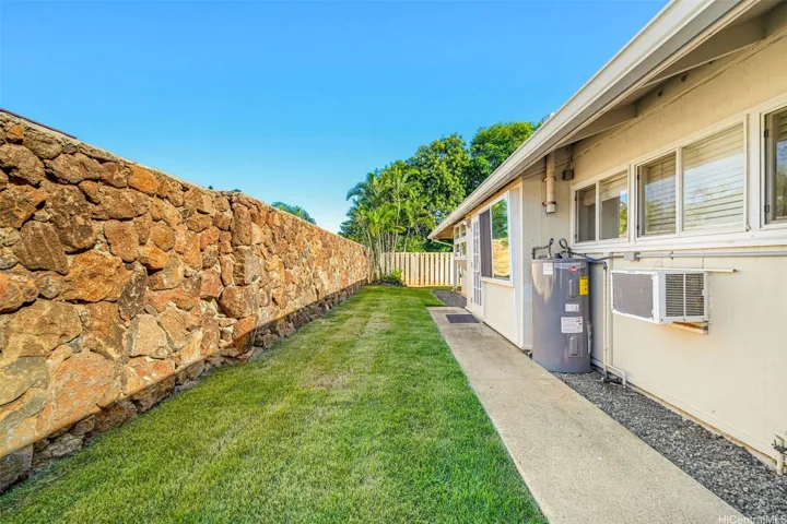 Main house backyard with lawn and stone wall.