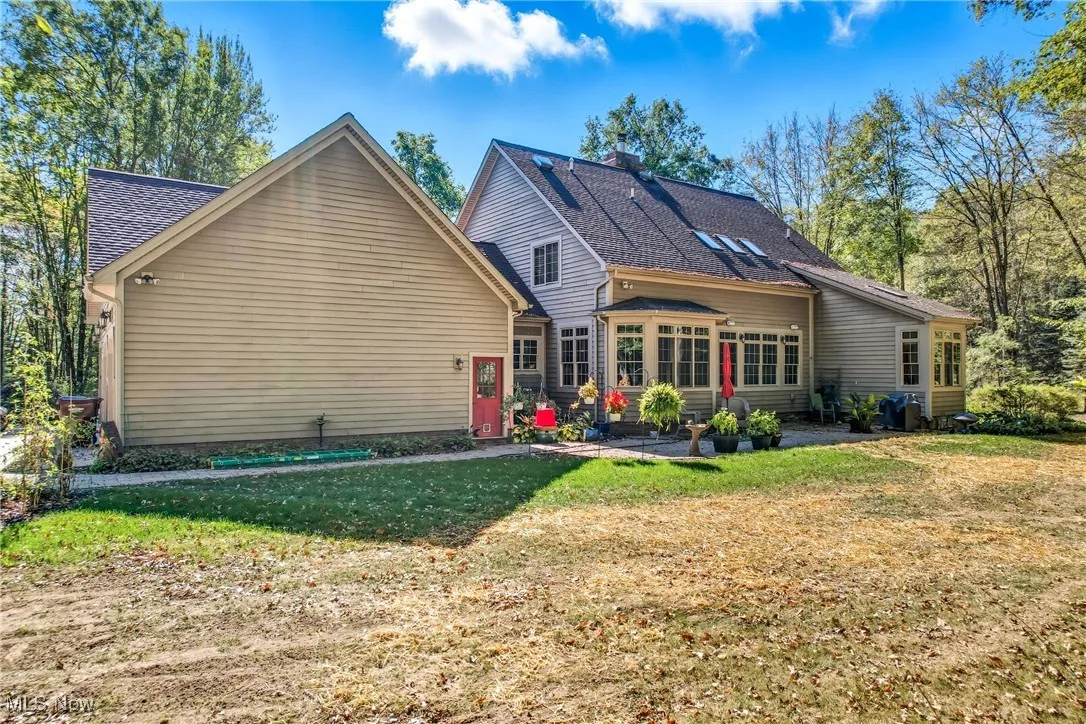 Back of property with a lawn, a chimney, and roof with shingles