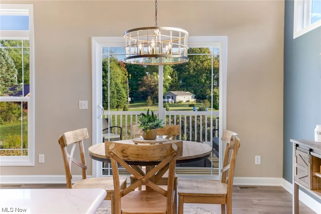 Wood floored dining room with a chandelier and a healthy amount of sunlight