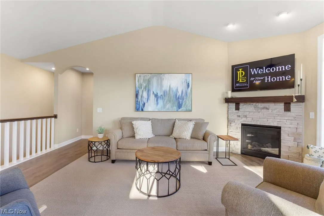 Living room featuring a fireplace, light hardwood flooring, and lofted ceiling