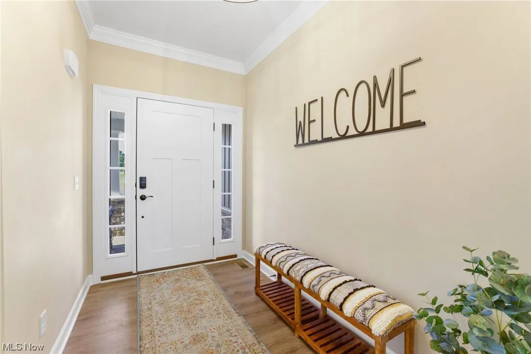 Hardwood floored foyer entrance with crown molding