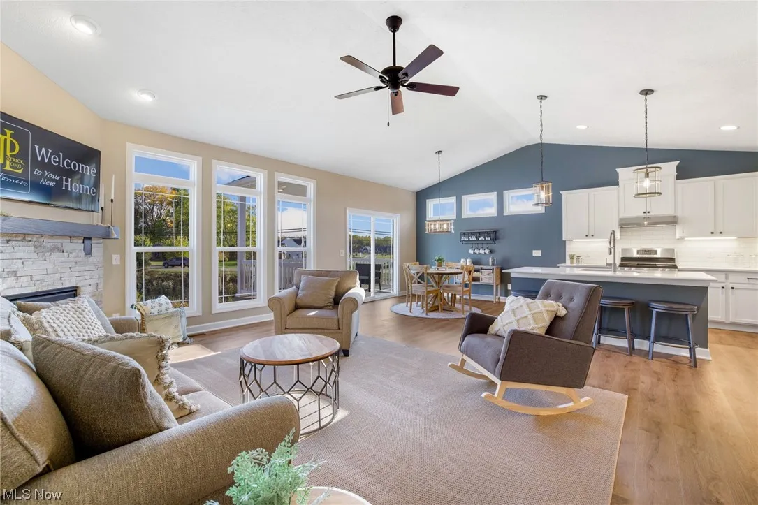 Living room with plenty of natural light, a fireplace, light hardwood flooring, and ceiling fan