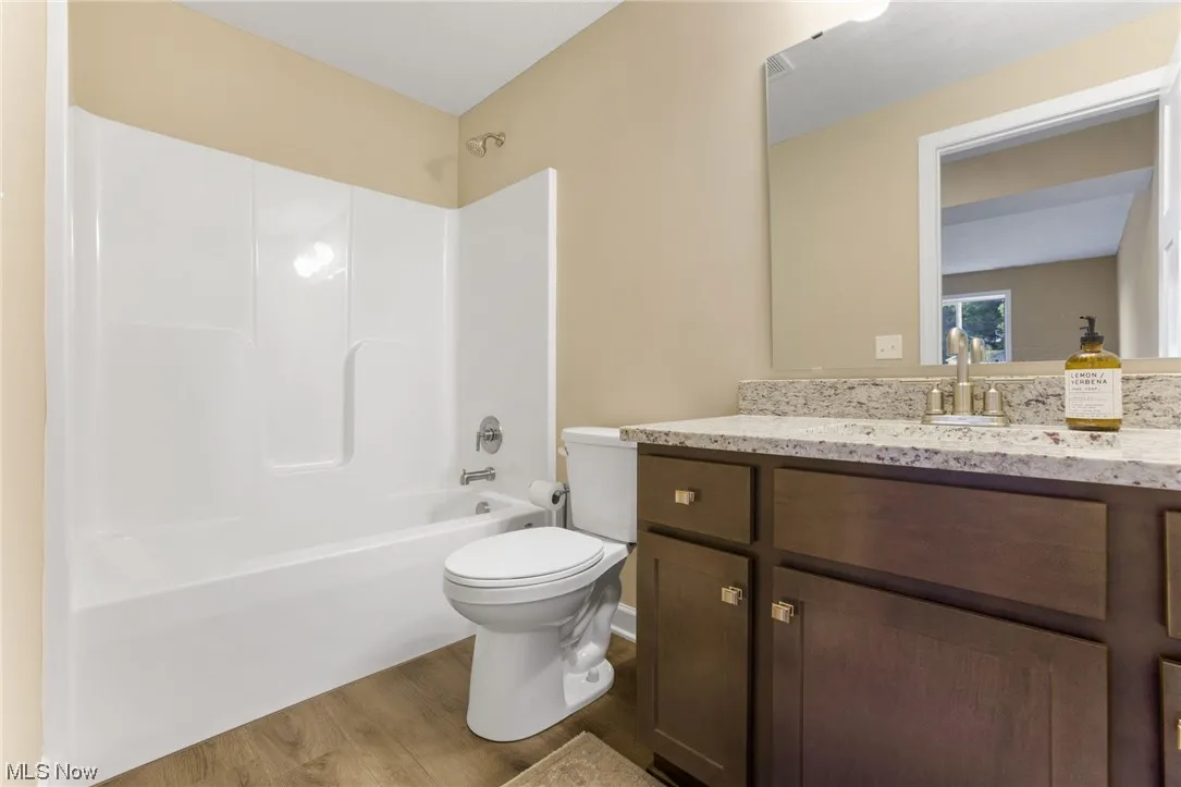 Full bathroom with shower / tub combination, vanity, hardwood floors, and toilet