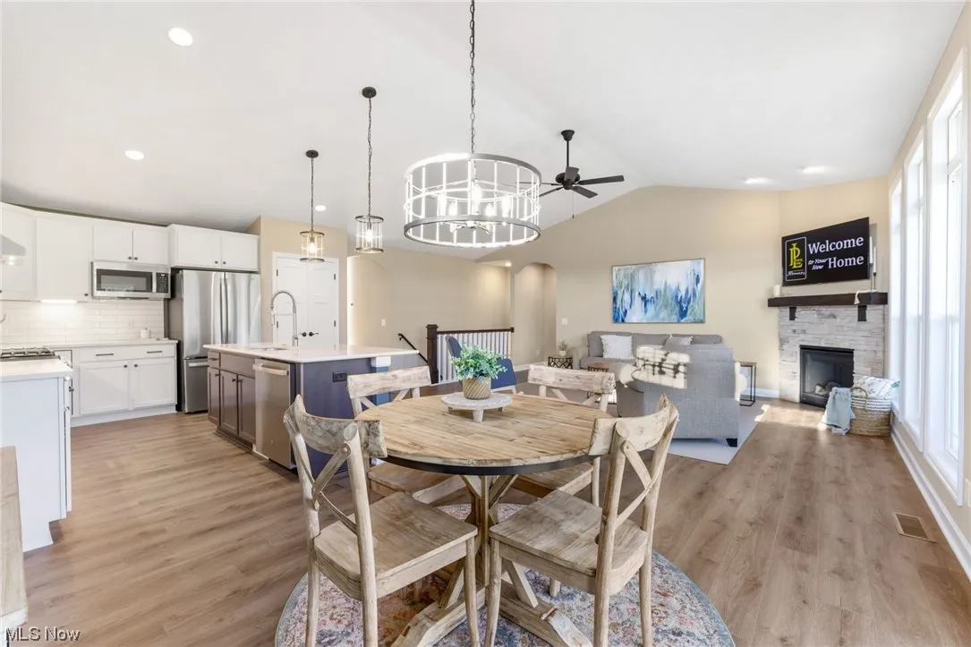 Dining space with lofted ceiling, sink, ceiling fan, and light hardwood flooring