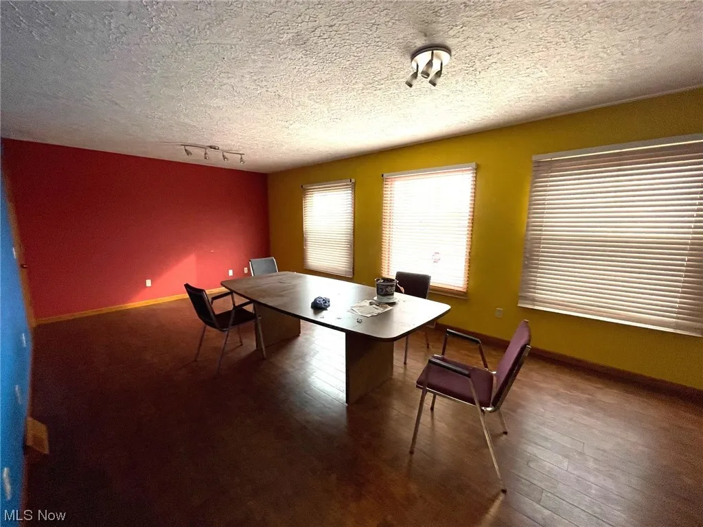 Dining space featuring a textured ceiling, dark hardwood floors, and rail lighting