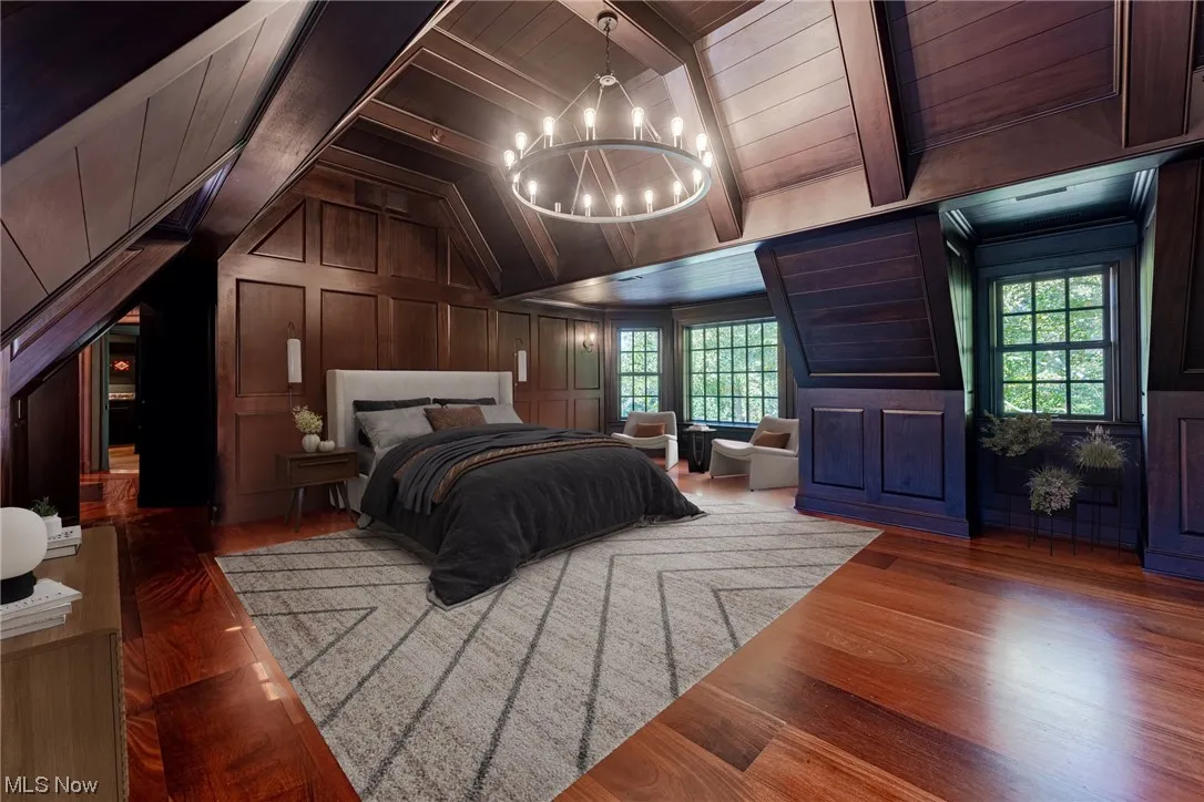 Hardwood floored bedroom with a notable chandelier, vaulted ceiling with beams, wood ceiling, and wooden walls