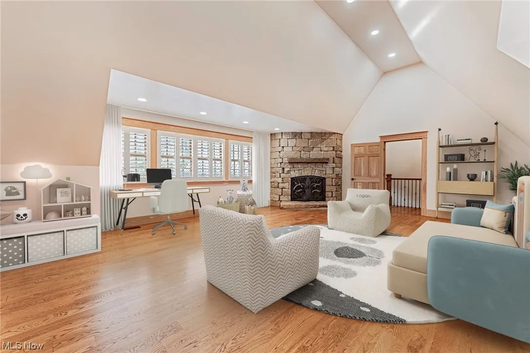 Living room with vaulted ceiling high, light hardwood floors, and a fireplace