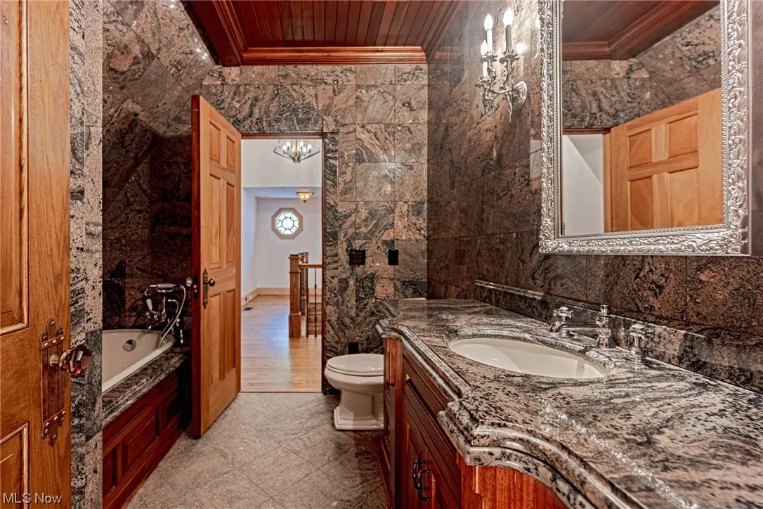 Bathroom with wood ceiling, toilet, crown molding, oversized vanity, and a bathtub
