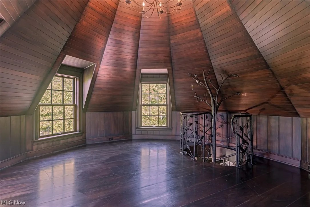Bonus room with wood ceiling, dark hardwood flooring, wooden walls, lofted ceiling, and a notable chandelier