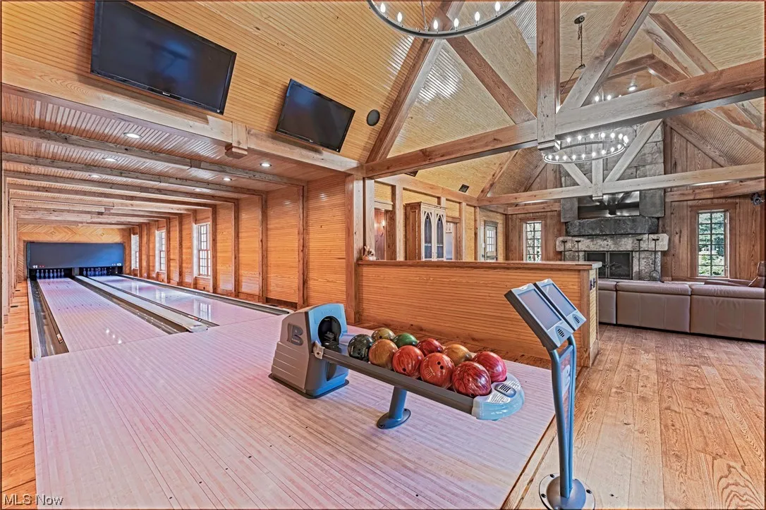 Rec room with light hardwood flooring, wood ceiling, and a bowling alley