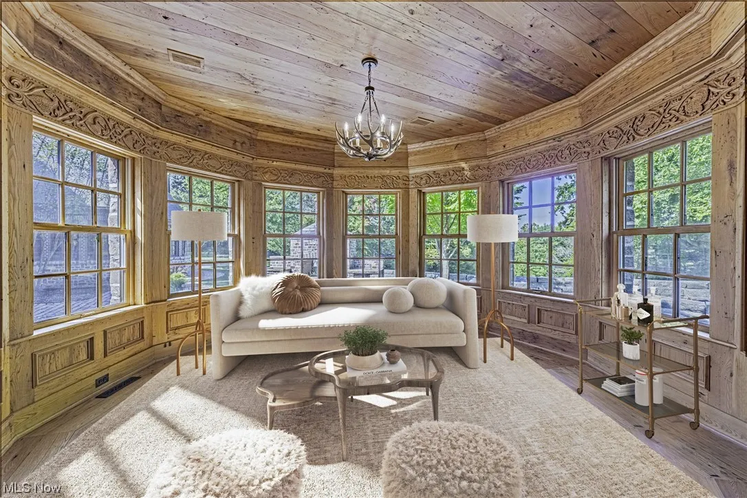 Hardwood floored living room with wood ceiling, a wealth of natural light, and a chandelier