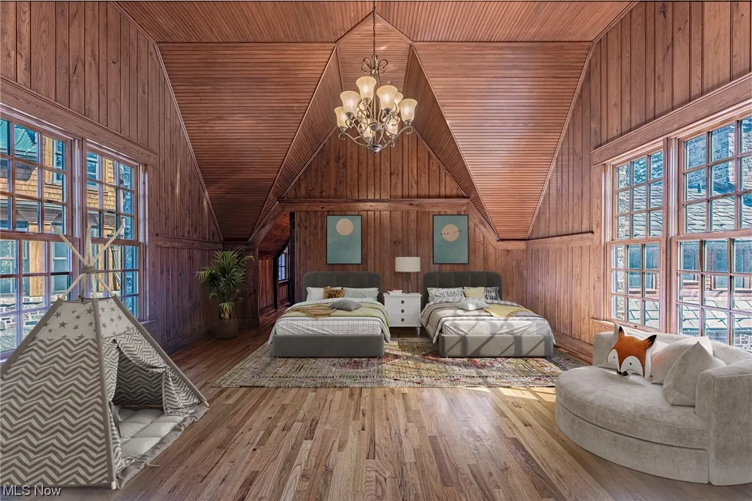 Living room featuring hardwood flooring, wooden walls, a notable chandelier, and wooden ceiling
