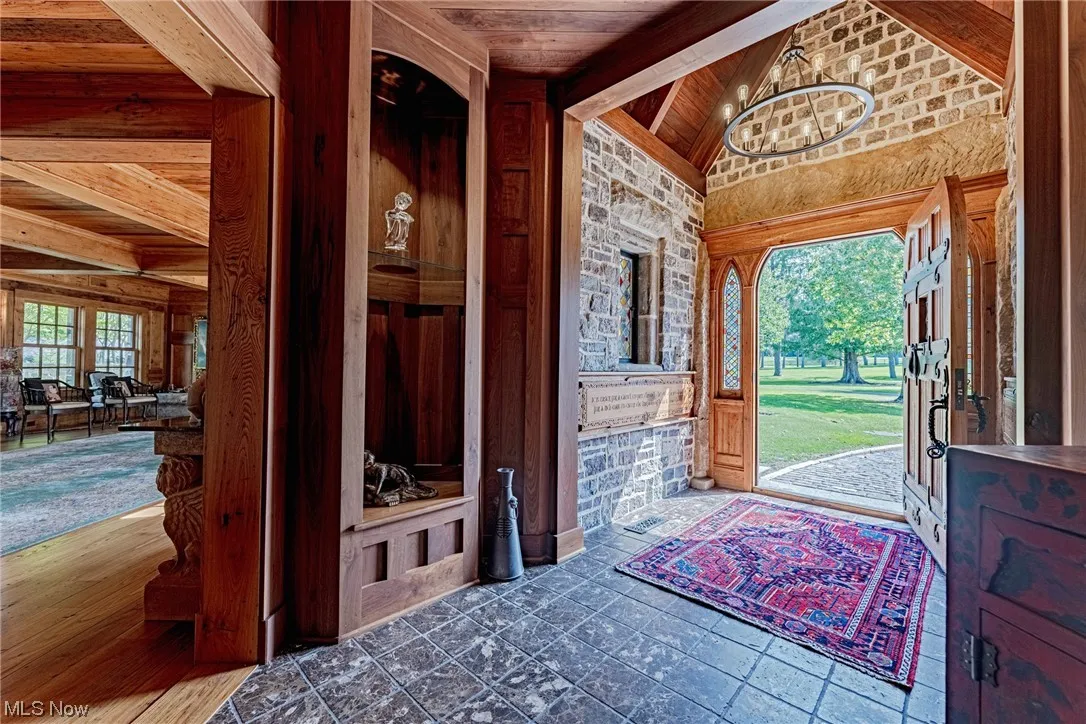 Entrance foyer with a chandelier, wood ceiling, dark tile floors, and lofted ceiling with beams