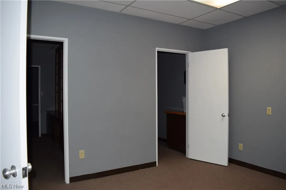 Carpeted spare room featuring a drop ceiling
