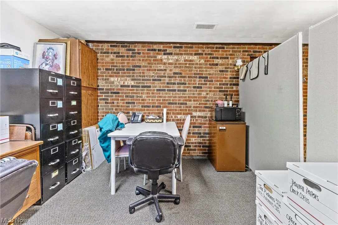 Office area featuring brick wall and carpet flooring