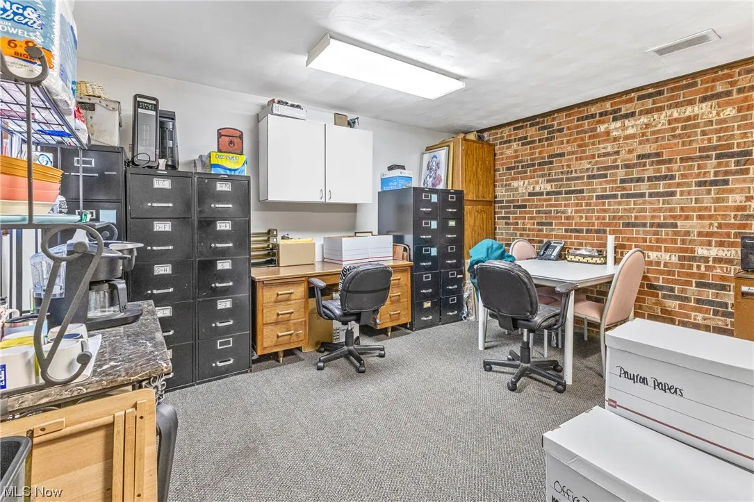 Carpeted office with brick wall