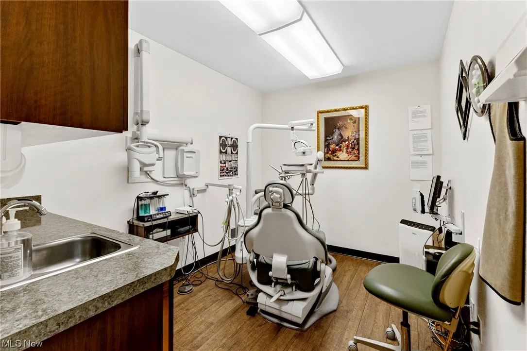 Treatment room featuring dark wood-type flooring and sink