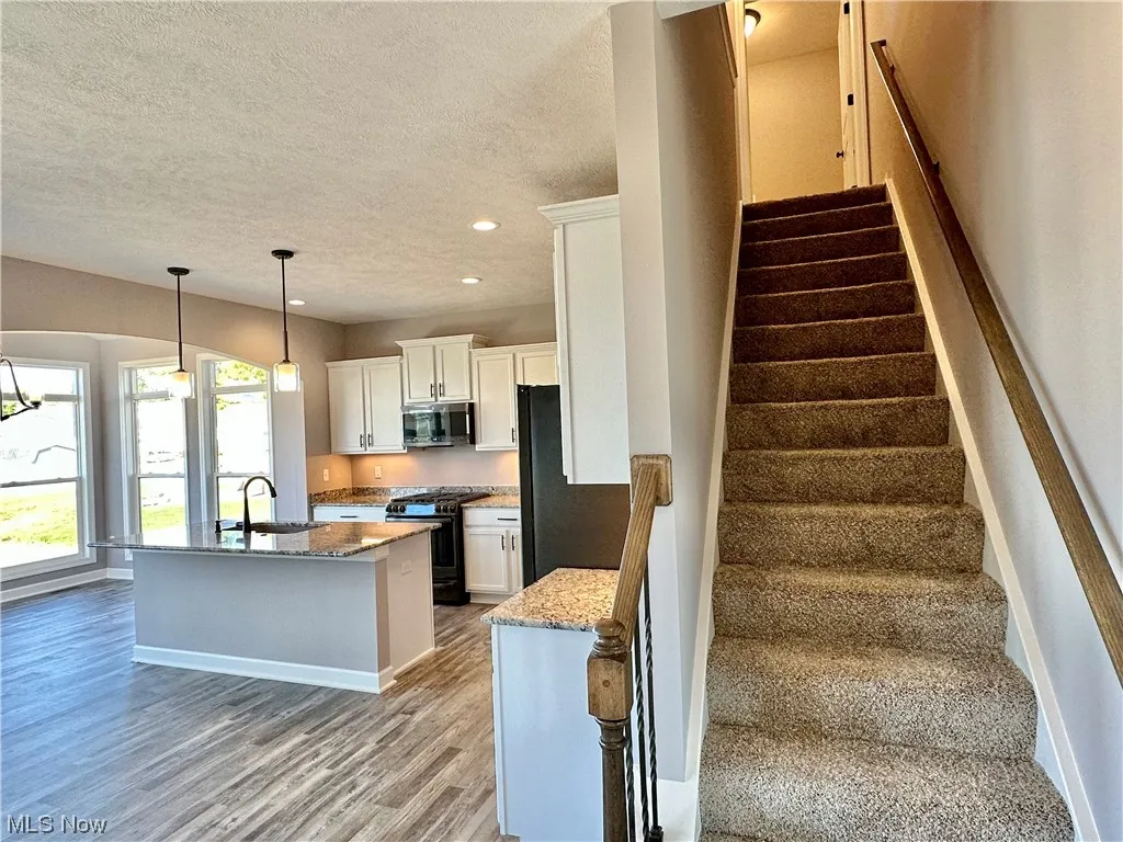 Stairway with sink, a textured ceiling, and light hardwood / wood-style flooring