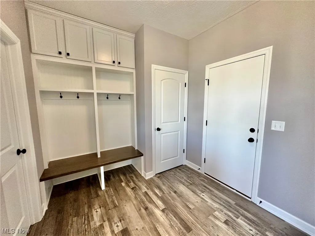 Mudroom featuring a textured ceiling and wood-type flooring
