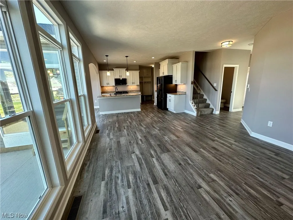 Unfurnished living room with dark hardwood / wood-style floors, a textured ceiling, and sink