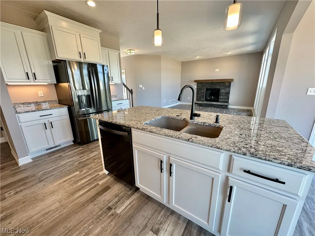 Kitchen featuring pendant lighting, a fireplace, white cabinets, and light wood-type flooring