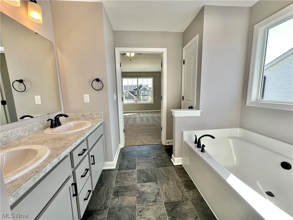 Bathroom featuring tile flooring, double sink vanity, and a tub