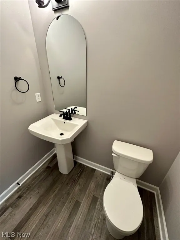 Bathroom with toilet, sink, and hardwood / wood-style floors