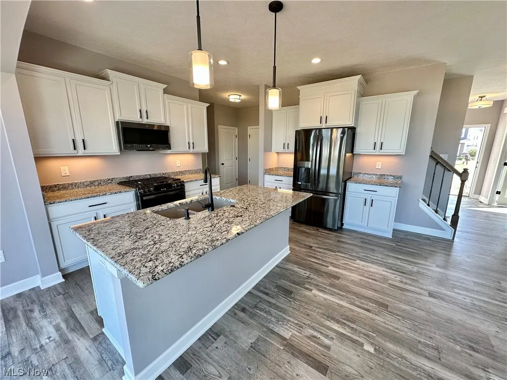 Kitchen with sink, hanging light fixtures, stainless steel appliances, dark hardwood / wood-style floors, and white cabinetry