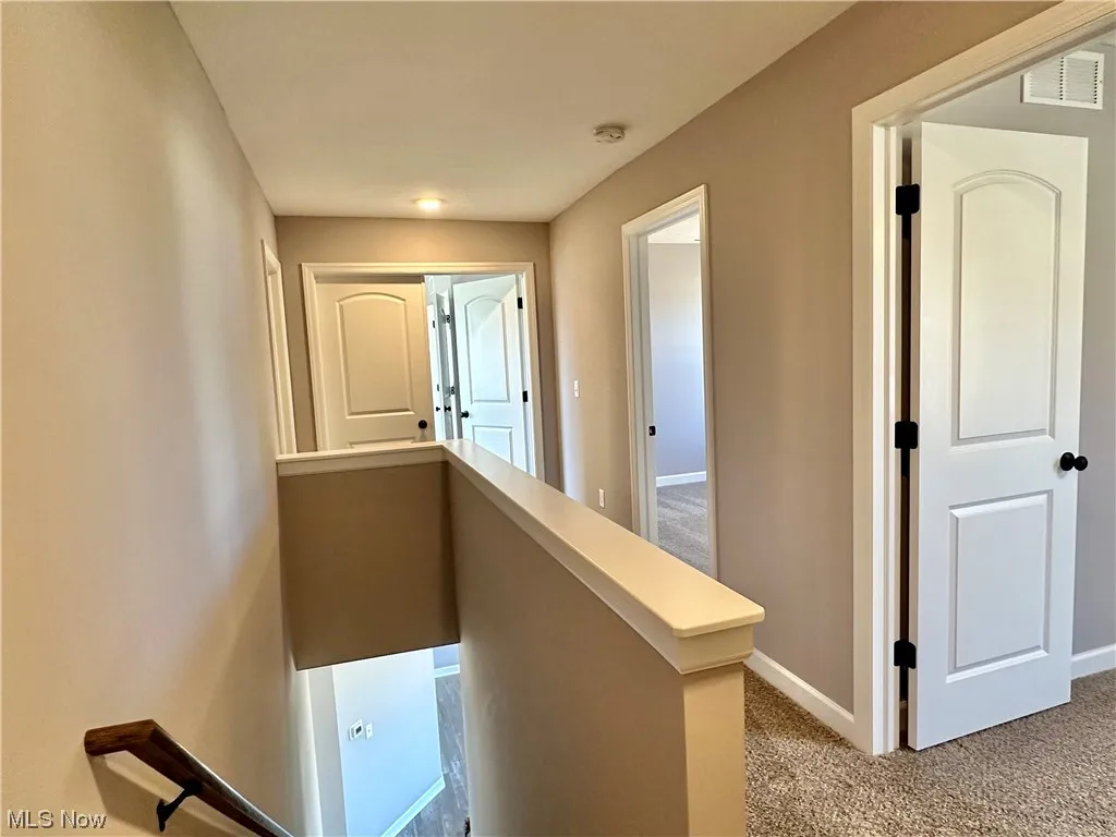 Hallway featuring light colored carpet