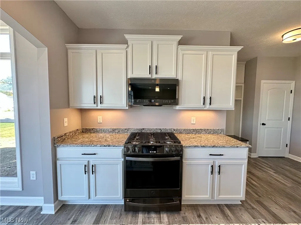 Kitchen featuring range with gas stovetop, wood-type flooring, and white cabinetry