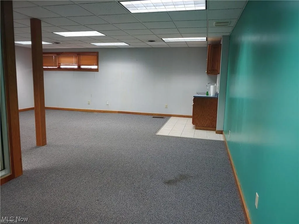 Basement with a paneled ceiling and light carpet