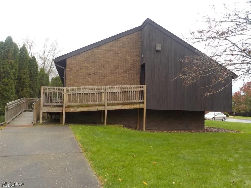 View of side of home featuring a lawn and a deck