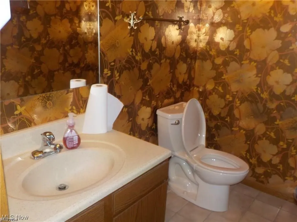 Bathroom featuring toilet, tile flooring, and vanity