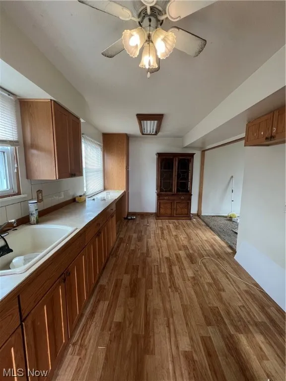 Kitchen with sink, ceiling fan, light hardwood / wood-style flooring, and backsplash