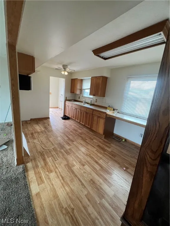 Unfurnished living room featuring ceiling fan, light wood-type flooring, and sink