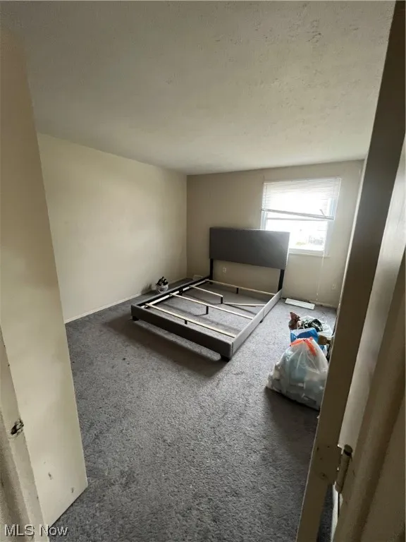 Bedroom featuring dark carpet and a textured ceiling