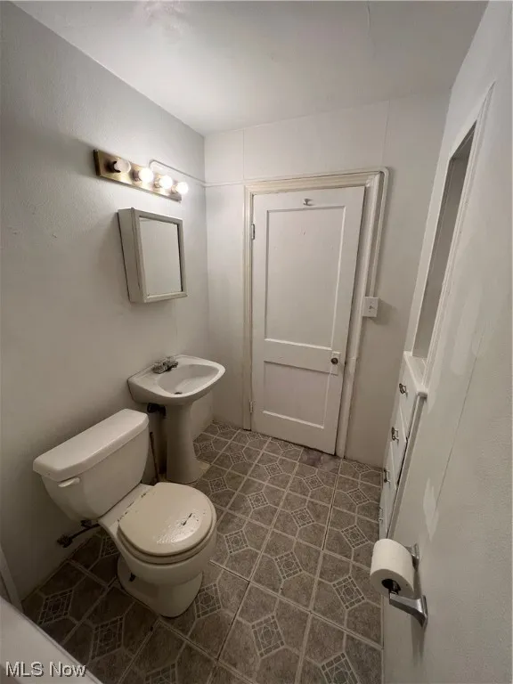 Bathroom with toilet, tile flooring, and sink