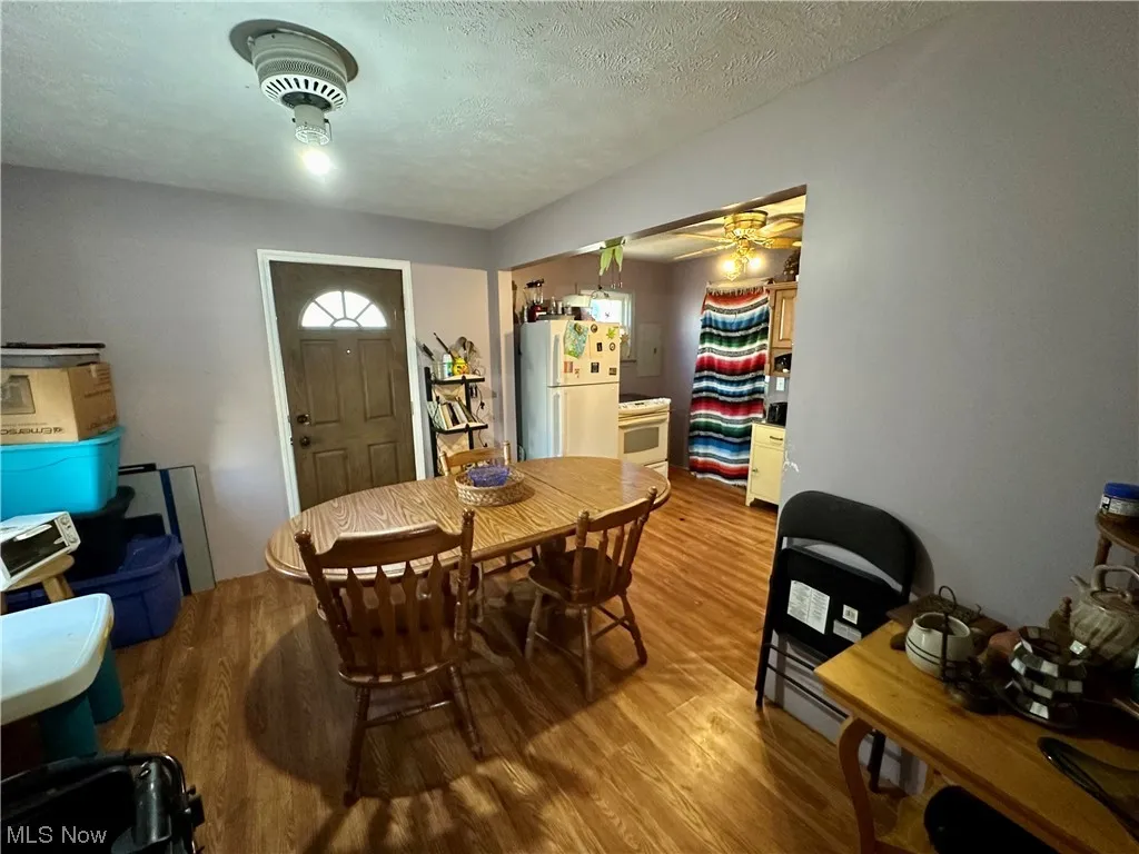 Dining room with ceiling fan, a textured ceiling, and hardwood / wood-style flooring
