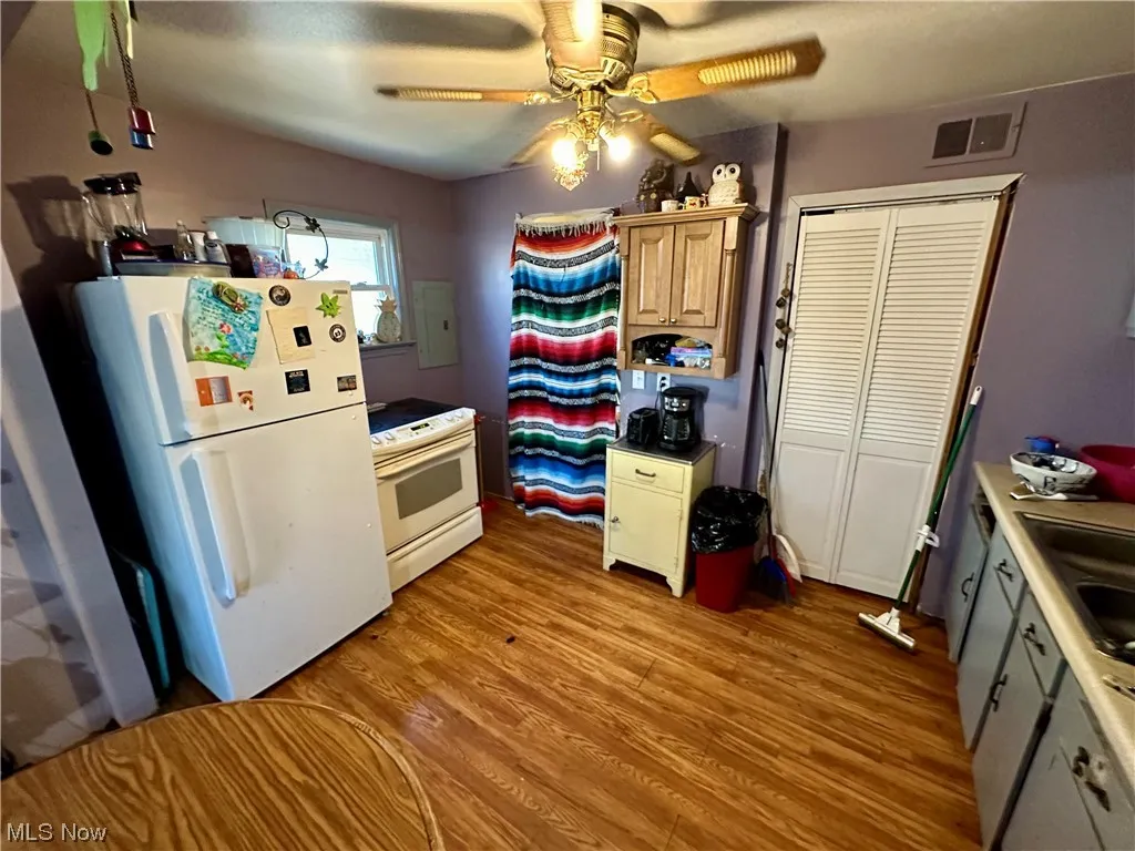 Kitchen with white appliances, ceiling fan, and light hardwood / wood-style floors