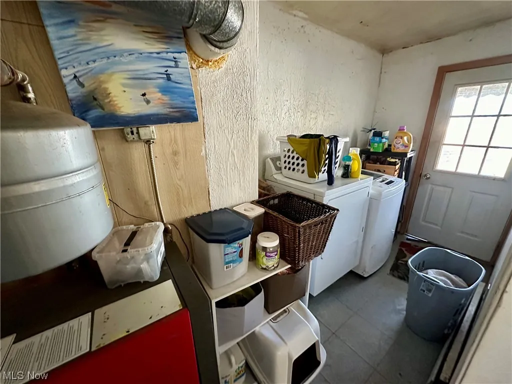 Clothes washing area featuring separate washer and dryer and dark tile floors