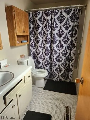 Full bathroom featuring toilet, shower / bath combo with shower curtain, tile flooring, and vanity