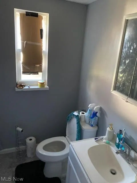 Bathroom featuring toilet, a wealth of natural light, tile floors, and vanity