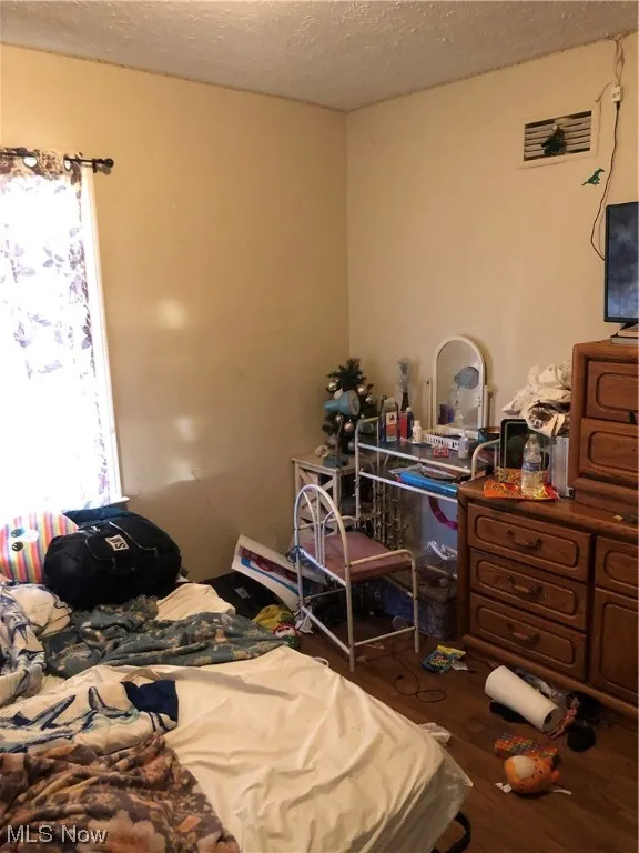 Bedroom with dark hardwood / wood-style floors and a textured ceiling