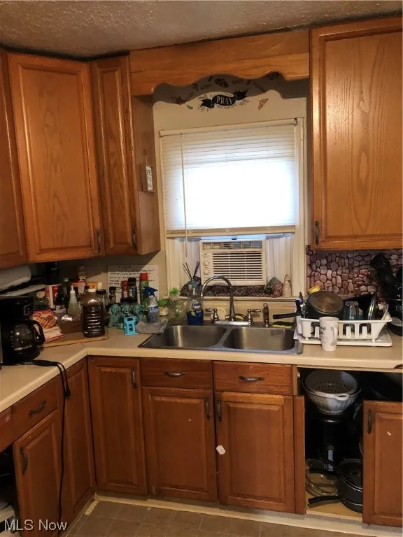 Kitchen featuring a textured ceiling, sink, and light tile floors