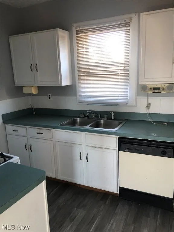 Kitchen featuring dishwashing machine, white cabinets, sink, and dark wood-type flooring