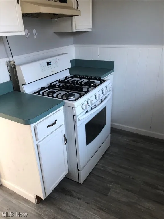 Kitchen with dark wood-type flooring, white cabinets, white gas range, and exhaust hood
